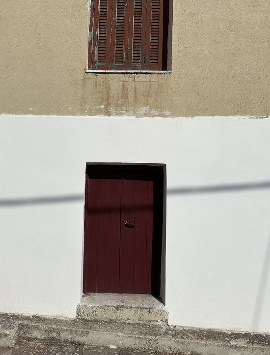 Small red door set into a beige wall with a white base.
